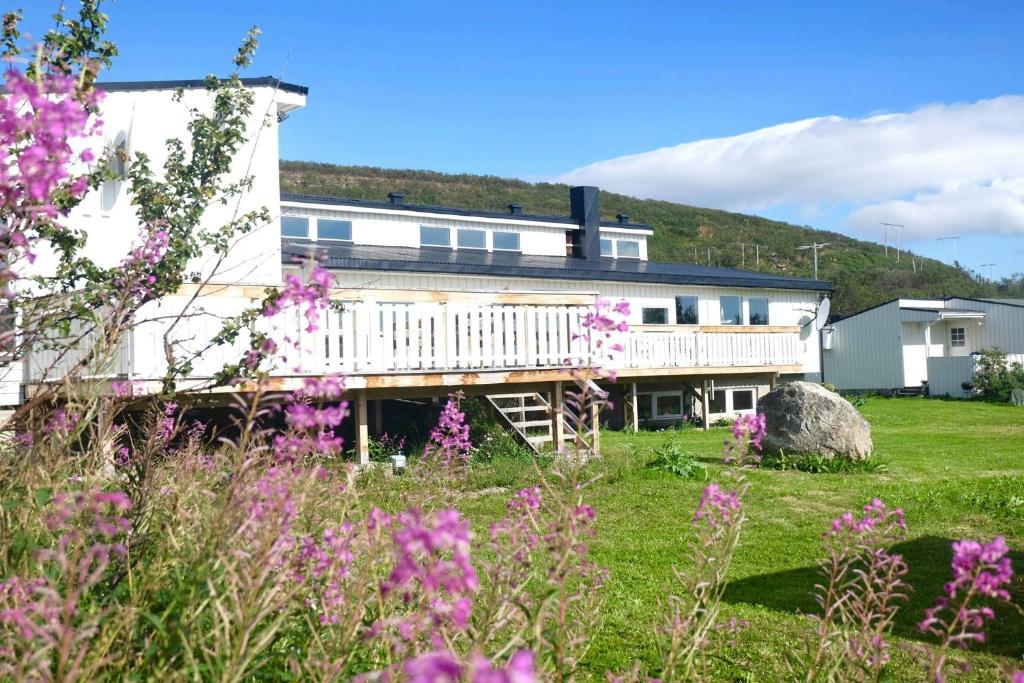 a building with a field of flowers in front of it at Varangertunet bed & breakfast in Jakobselv