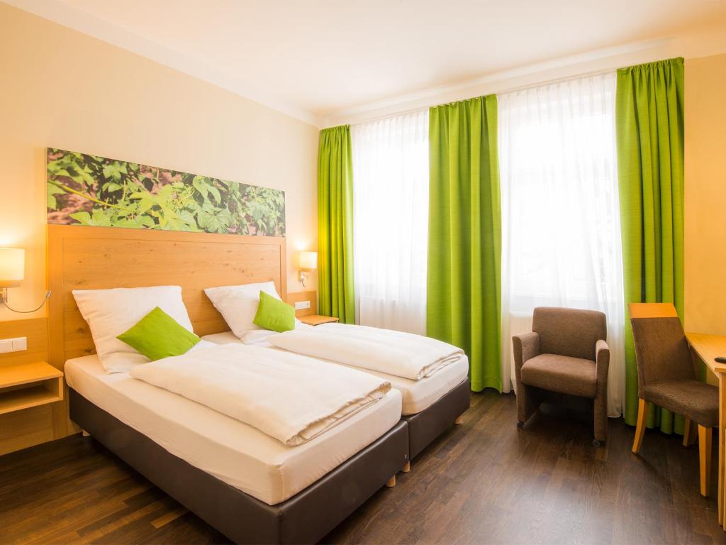 ein Hotelzimmer mit 2 Betten und einem Stuhl in der Unterkunft Hotel Brauereigasthof Amberger in Kösching