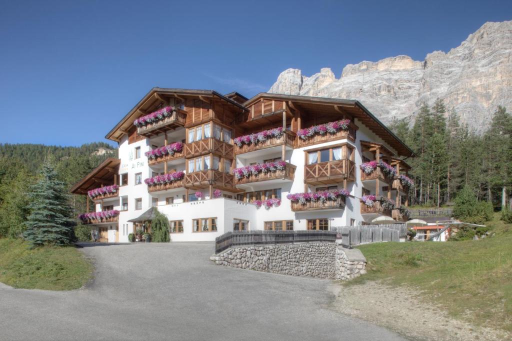 a building with flowers on the balconies of it at Hotel Ciasa Ai Pini in San Cassiano