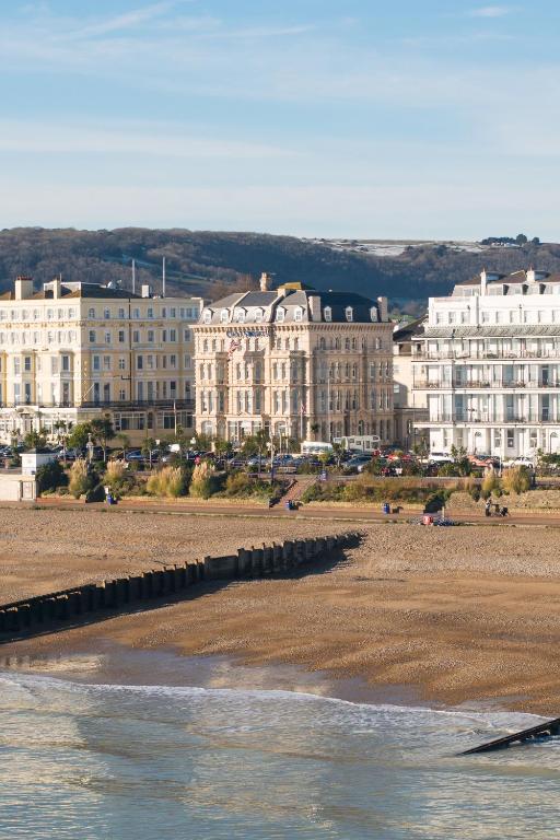 a group of buildings on a beach next to the water at The Chatsworth Hotel in Eastbourne