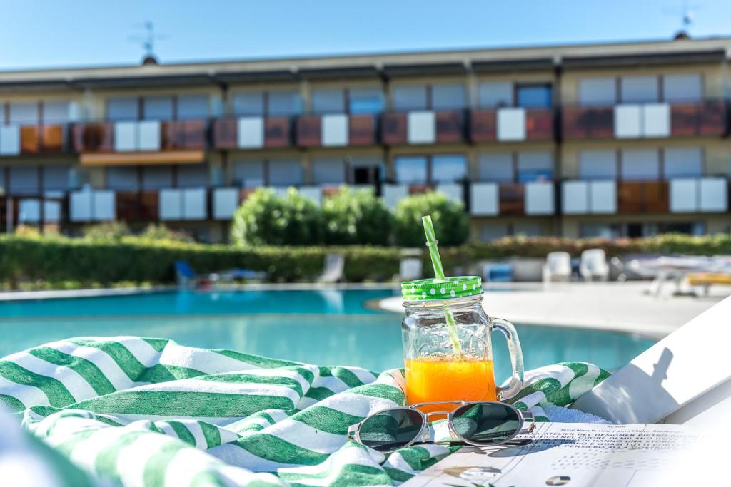 a glass jar of orange juice sitting on a table with sunglasses at Callas Family Apartment in Sirmione