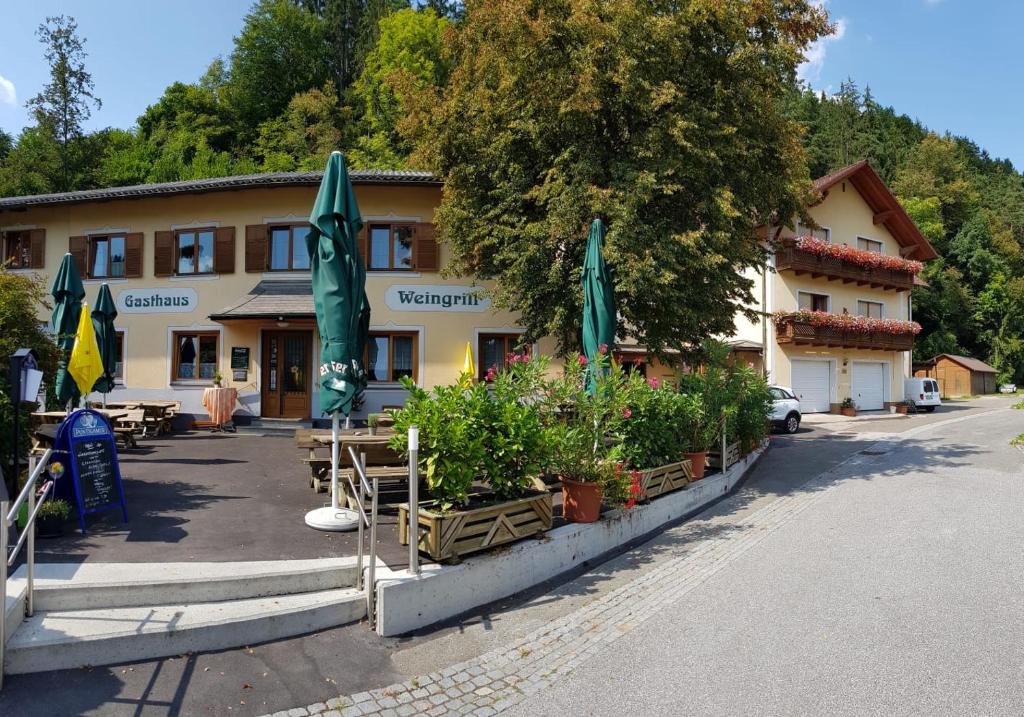 ein Gebäude mit Pflanzen und Sonnenschirmen davor in der Unterkunft Gasthof Weingrill in Friesach