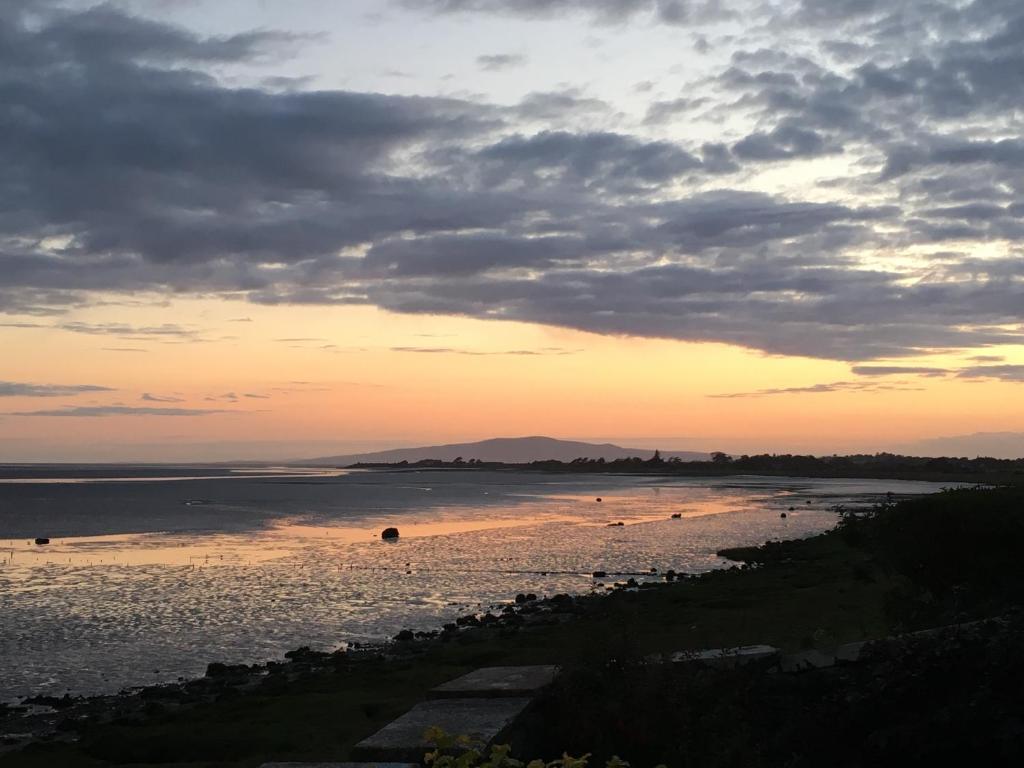 einen Sonnenuntergang über einem Strand mit Menschen im Wasser in der Unterkunft The Waterside Rooms in Annan