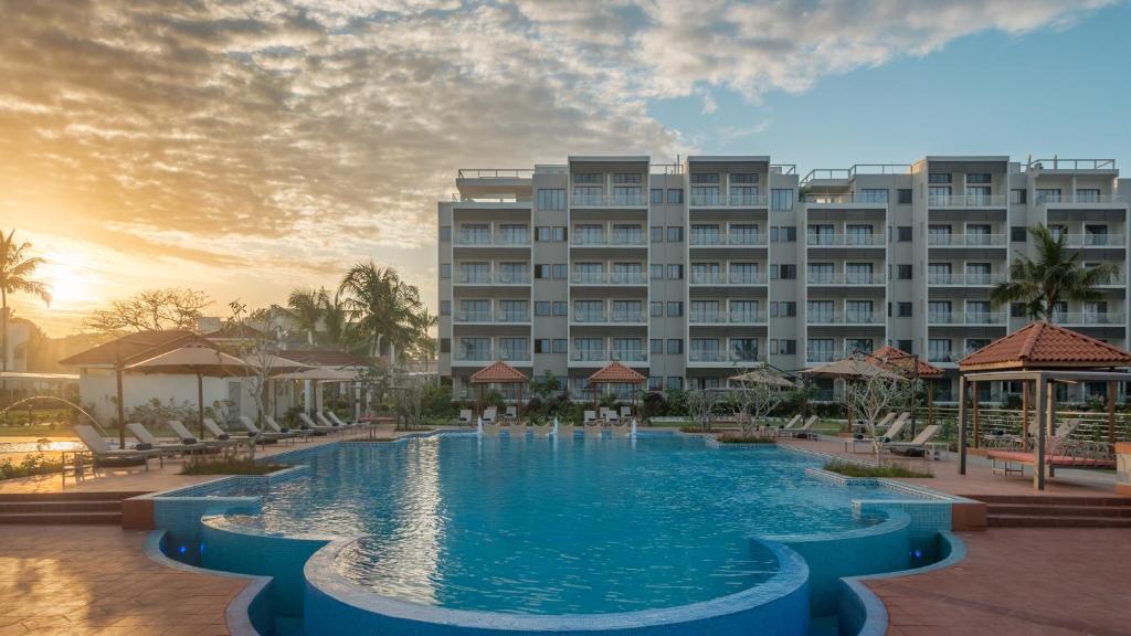 a hotel with a large swimming pool in front of a building at Hotel Verde Zanzibar - Azam Luxury Resort and Spa in Zanzibar City