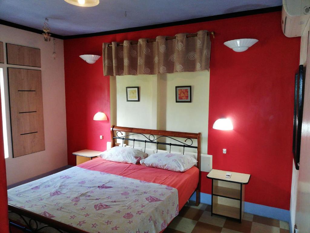 a red bedroom with a bed with red walls at Villa Acajou sur Mer in Rodrigues Island