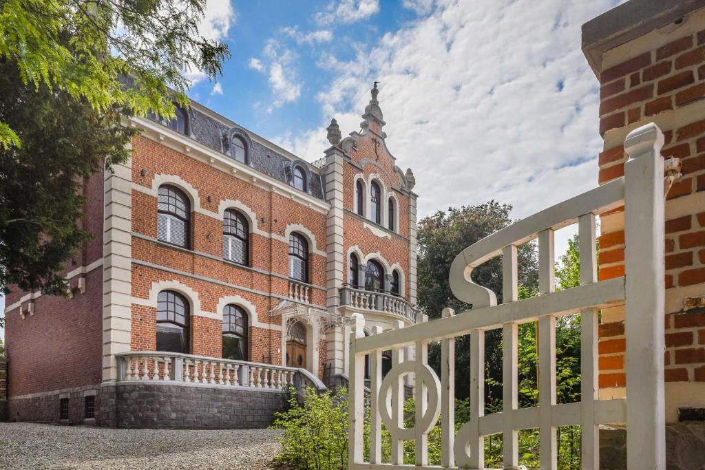 a brick building with a white fence in front of it at Villa Copis in Borgloon