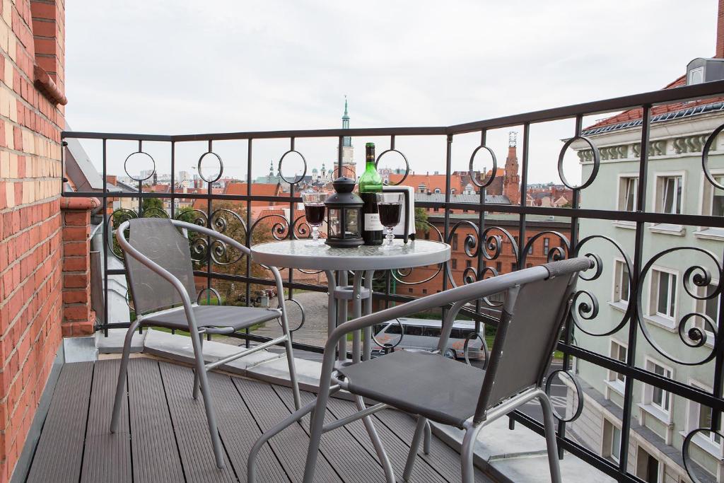 a table and chairs on a balcony with a view at Living Apartments Poznań in Poznań