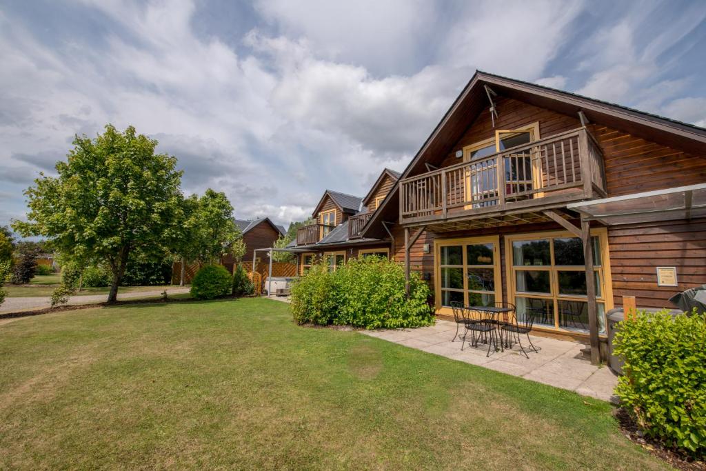 a log home with a deck and a yard at Loch Lomond Waterfront Luxury Lodges in Balmaha