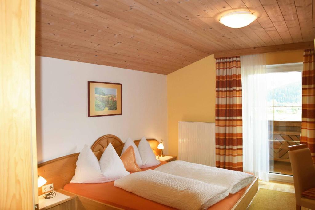 a bedroom with a bed with white sheets and a window at Ferienhaus Steger Maria in Flachau