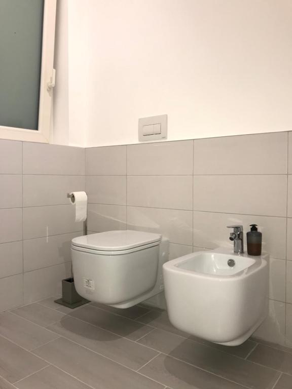 a white bathroom with a toilet and a sink at Bari Lory’s Home in Bari