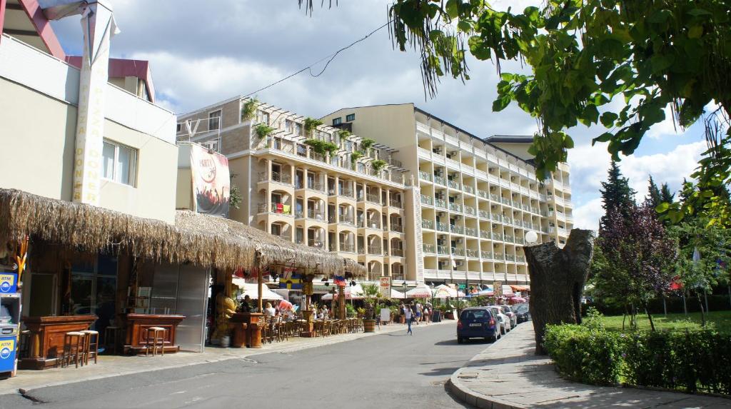 una calle con un edificio, mesas y sillas en Miramar Front Beach Self Catering Apartments No Swim Pool Access, en Sunny Beach