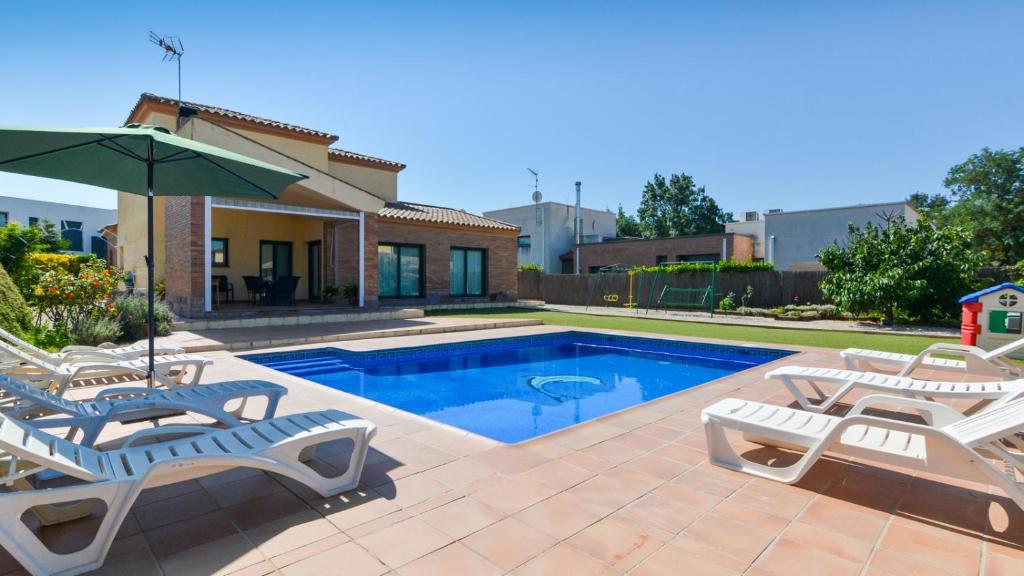 a swimming pool with two lounge chairs and an umbrella at Casa Cerca De La Playa in Vidreres