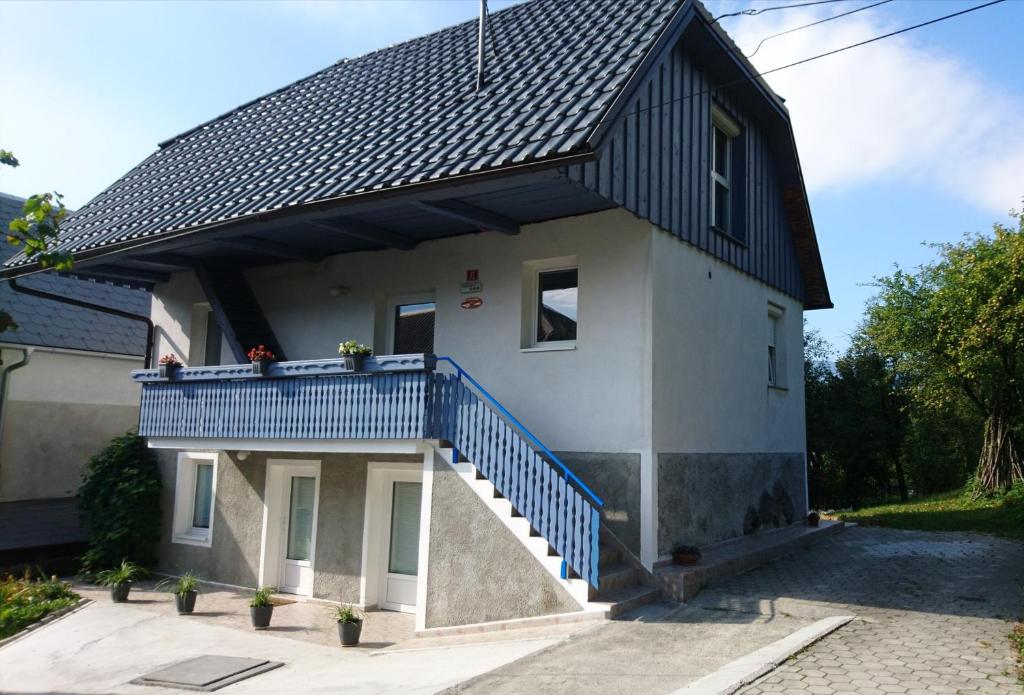a house with a black roof and a blue balcony at Apartments Rupnik in Bovec