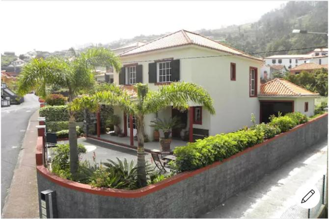 a house with palm trees in front of a street at Moradia Ponte de Pedra in São Vicente