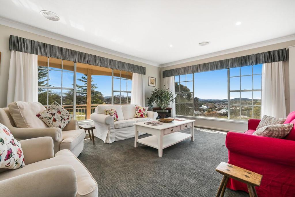 a living room with white furniture and large windows at A House With A View, Molong. NSW in Molong