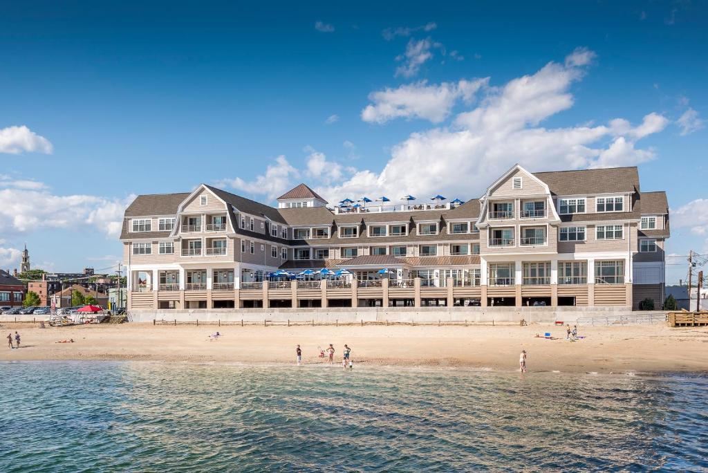 a large building on a beach next to the water at Beauport Hotel Gloucester in Gloucester