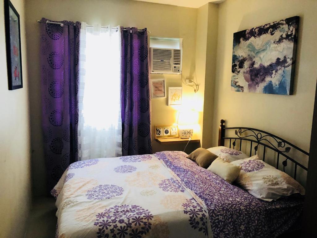 a bedroom with a bed with purple curtains and a window at Contemporary cozy 6- 2BR Apartment in Davao City