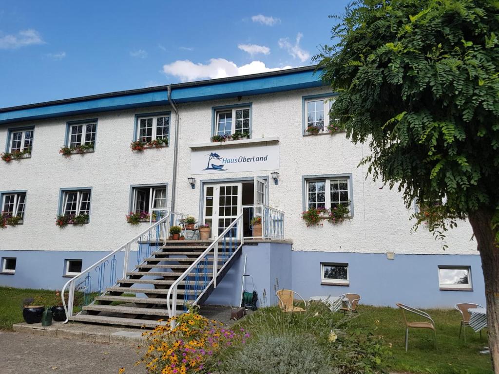 a white building with stairs in front of it at Haus ÜberLand in Sundhagen-Niederhof
