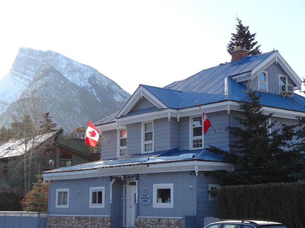 a blue house with a mountain in the background at Three Peaks Banff in Banff