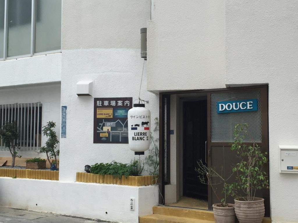 Una porta di un edificio con un cartello che dice di Douce a Ginowan