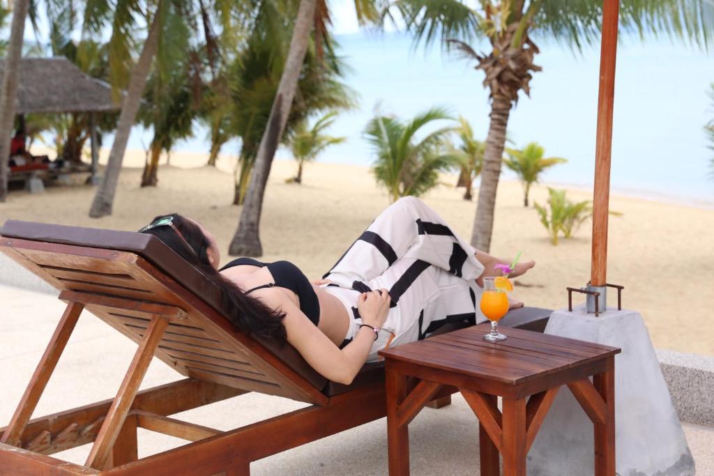 Eine Frau, die auf einem Stuhl am Strand liegt. in der Unterkunft Shangrilah Bungalow in Mae Nam