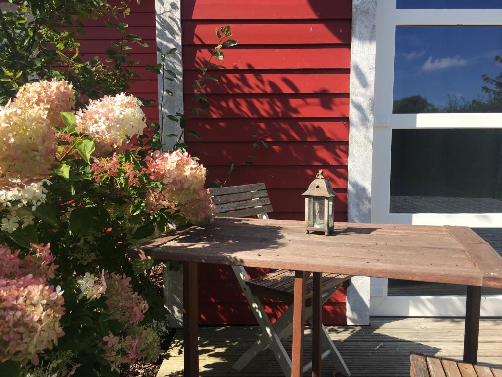 einem Holztisch mit einer Laterne neben einem roten Gebäude in der Unterkunft Ostsee Schwedenhäuser in Breege