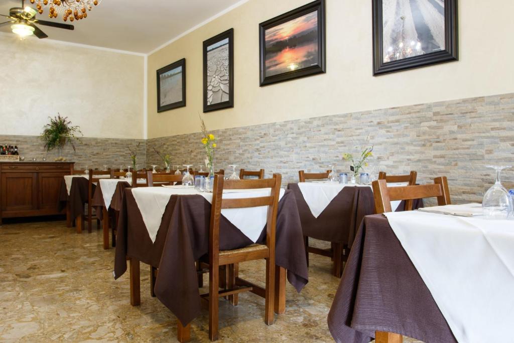 Locanda con cucina Il Tornado في Gramignazzo: غرفة طعام مع طاولات وكراسي وجدار من الطوب