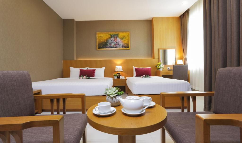 a hotel room with two beds and a table and chairs at Golda Hotel in Ho Chi Minh City
