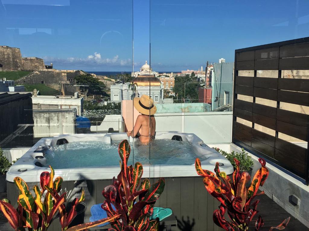 352 Guest House Hotel Boutique في سان خوان: رجل يجلس في حوض استحمام ساخن فوق المبنى