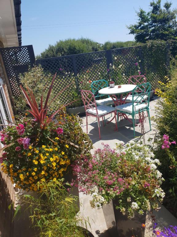 a patio with a table and chairs and flowers at Goshens Farm B&B in Wootton