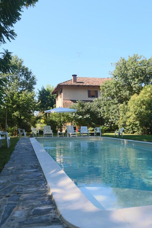 a swimming pool with chairs and a house in the background at Locanda Del Molino Vecchio in Magliano Alfieri