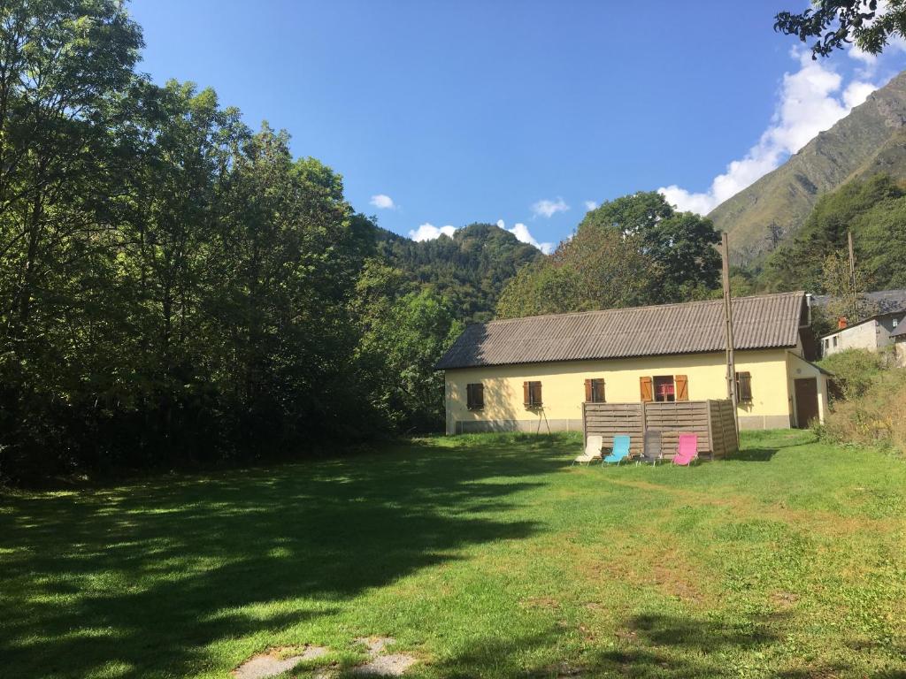 a house in a field with mountains in the background at Gîte Espace et Montagne in Aragnouet