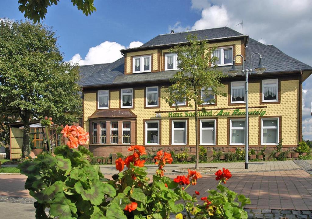 un edificio giallo con fiori rossi di fronte di Pension Haus Saarland a Oberhof