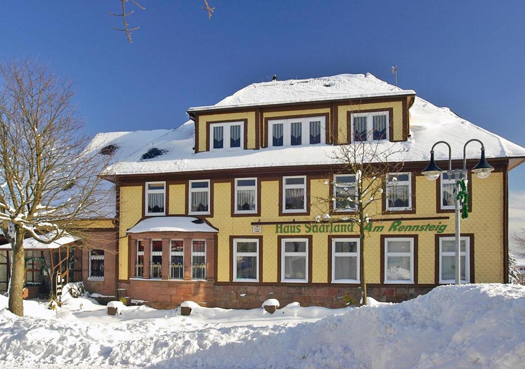 a large yellow building with snow on top of it at Pension Haus Saarland in Oberhof