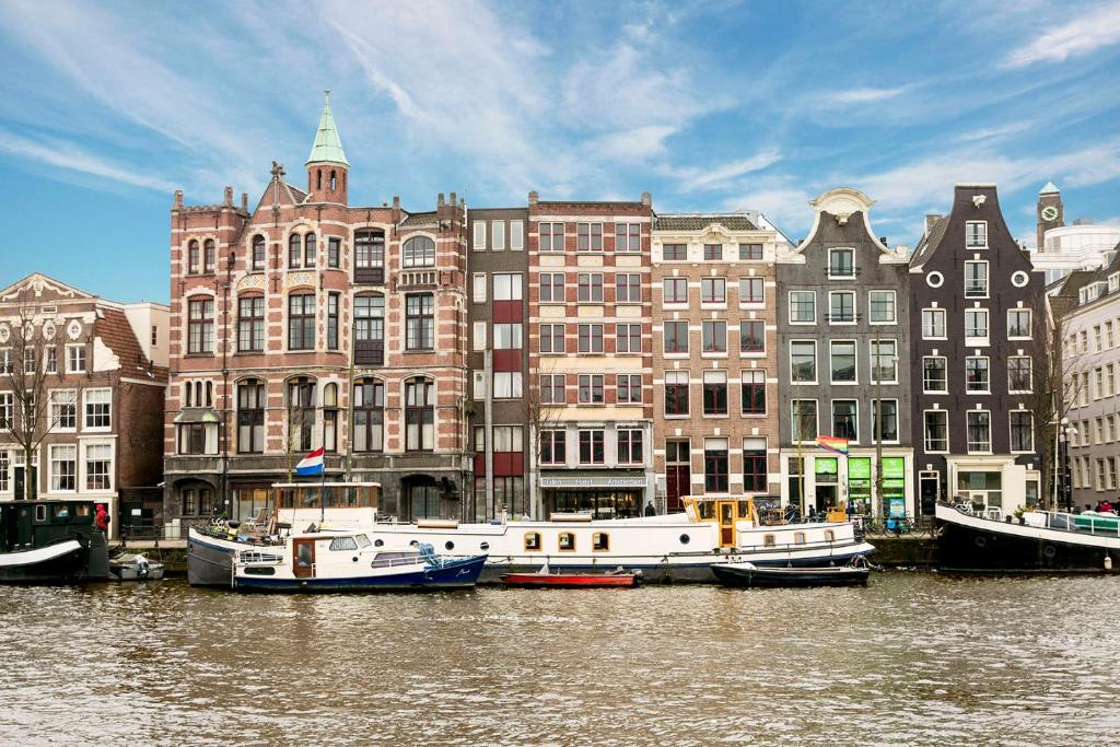 un grupo de barcos atracados en el agua frente a los edificios en Eden Studios and Apartments en Ámsterdam