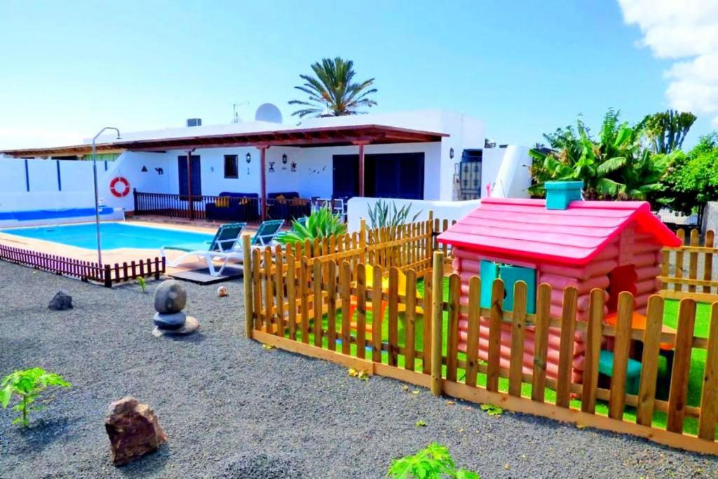 una valla de madera frente a una casa con piscina en Villa Raima, en Playa Blanca