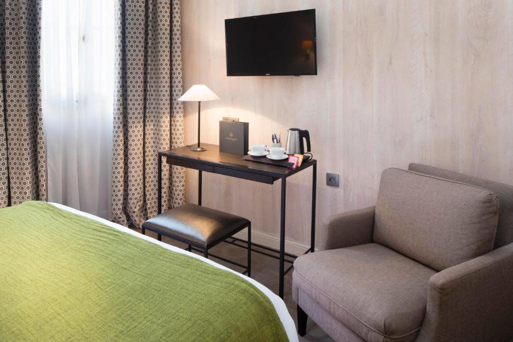 a room with a bed and a chair and a television at Hôtel du Danube Saint Germain in Paris