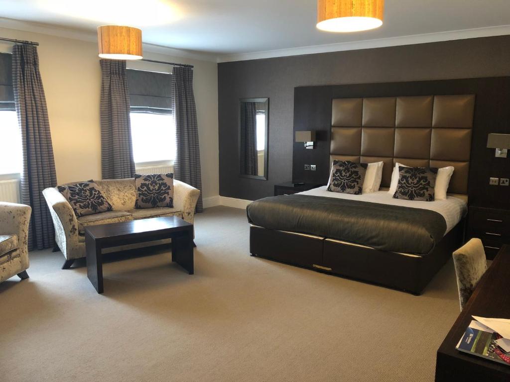 a bedroom with a bed and a couch and a chair at Lion Hotel in Worksop