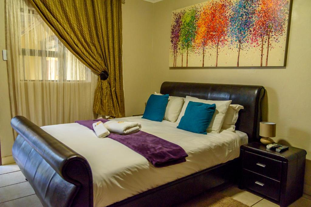 ein Schlafzimmer mit einem Bett mit blauen Kissen in der Unterkunft Hlulani Guest House in Northam