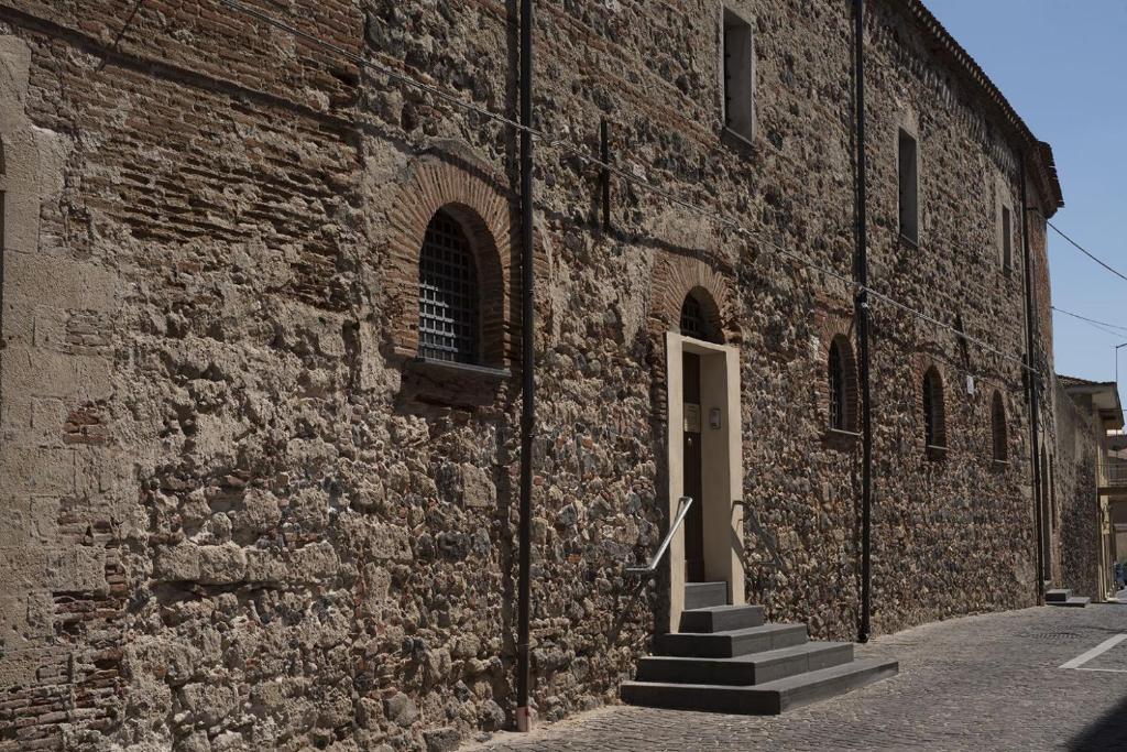 un edificio de ladrillo con escaleras que conducen a una puerta en Monastero Santa Chiara Guest House, en Oristano