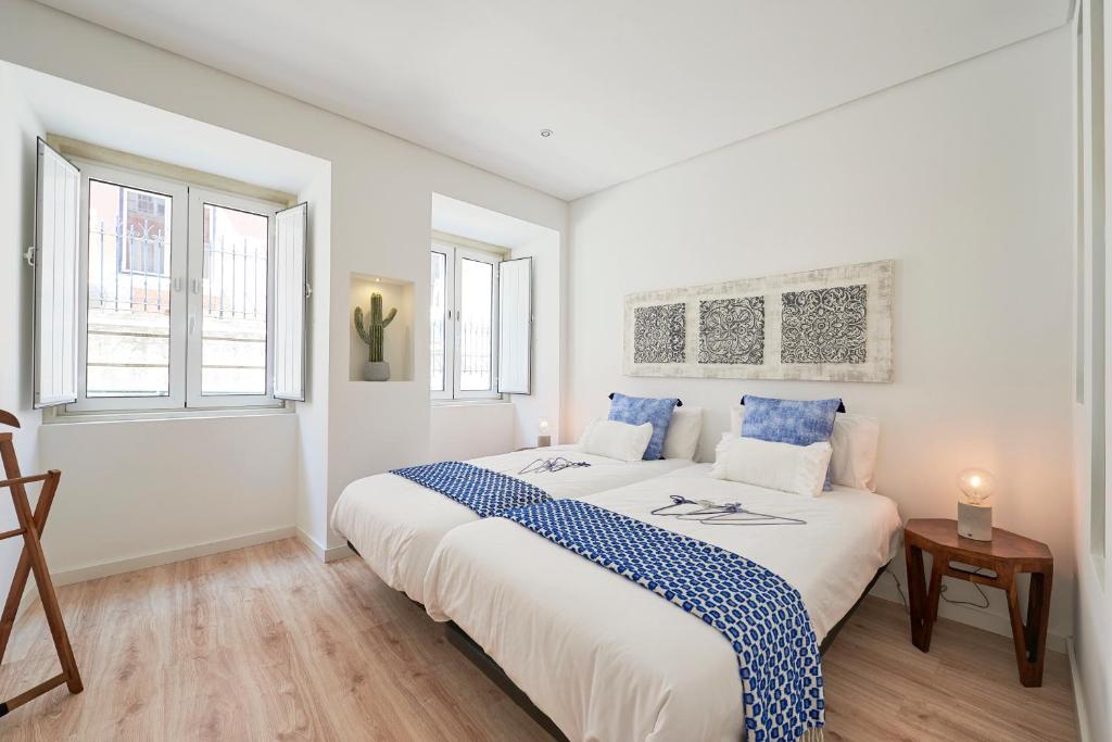 una camera bianca con un grande letto e due finestre di Avenida da Liberdade Apartment a Lisbona