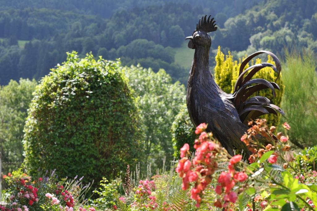 a statue of a rooster in a garden at Hôtel Restaurant Taillard in Goumois
