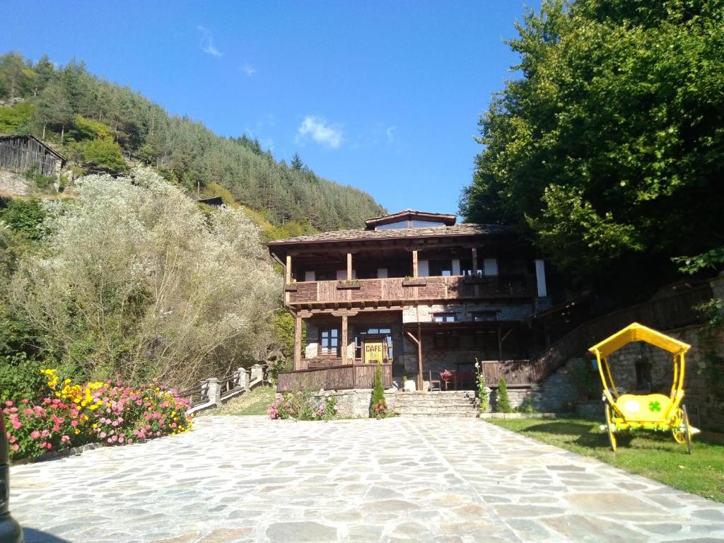 una casa con un patio de juegos amarillo delante de ella en Kyshta za Gosti Gospodevi, en Gorno Dryanovo