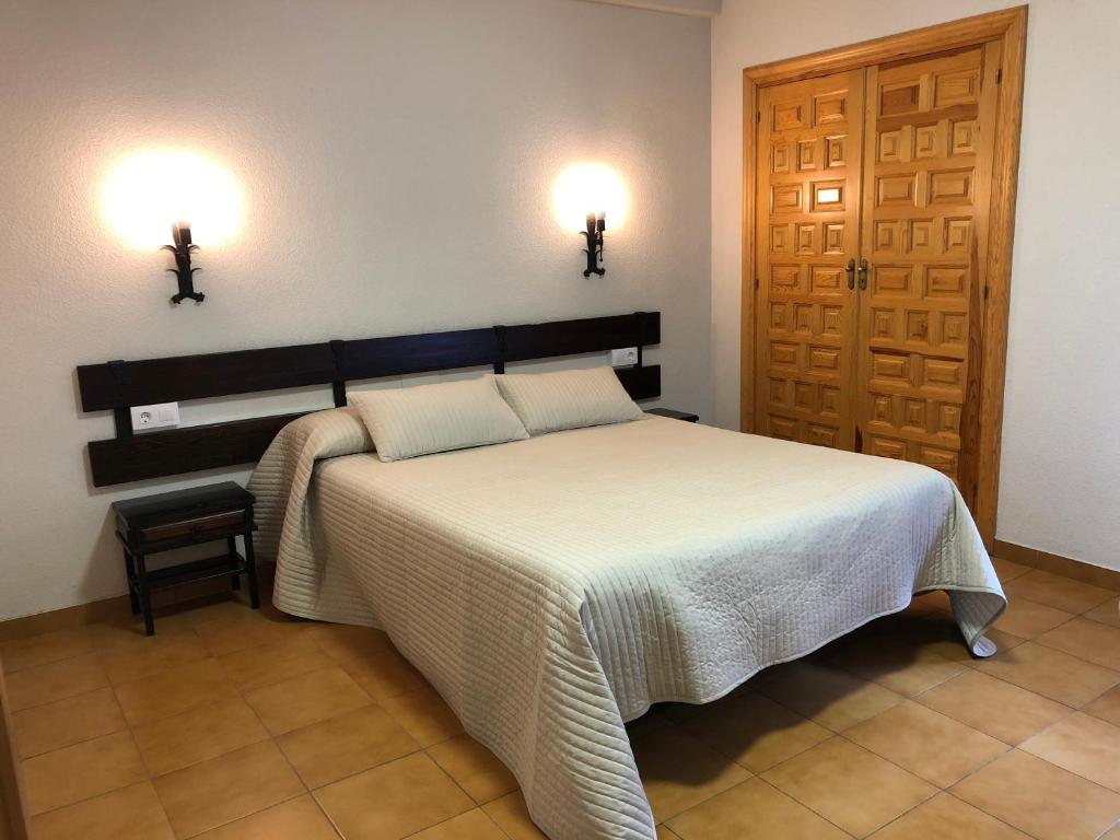 a bedroom with a bed and two lights on the wall at Hotel La Venta de Goyo in Viniegra de Abajo