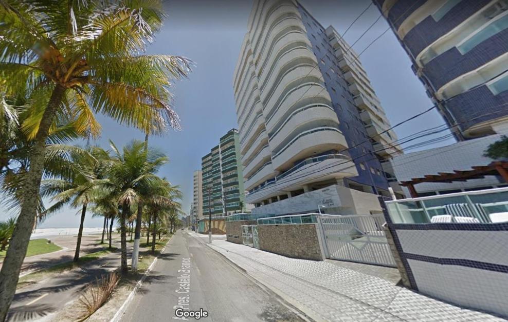 a street with palm trees and a tall building at Apartamento Praia Grande Pé na areia in Solemar