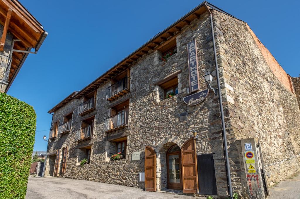 Um velho edifício de pedra com um sinal. em Aparthotel les Corts em Llivia