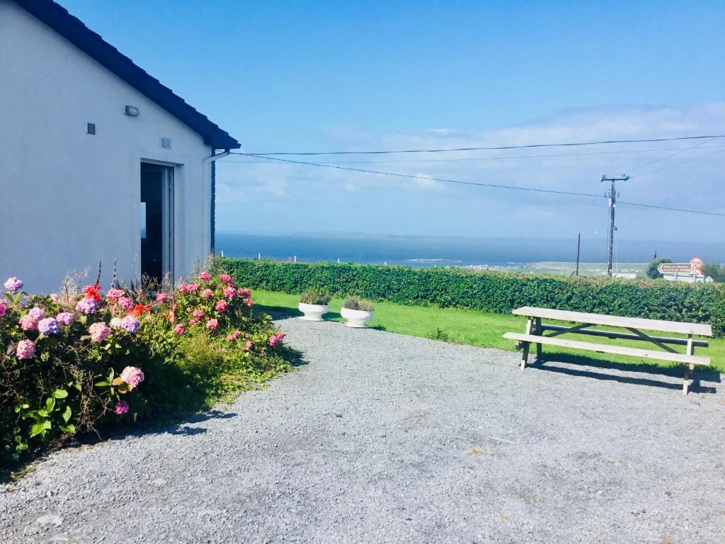 una panchina seduta accanto a un edificio con fiori di Doolin View Apartment a Doolin