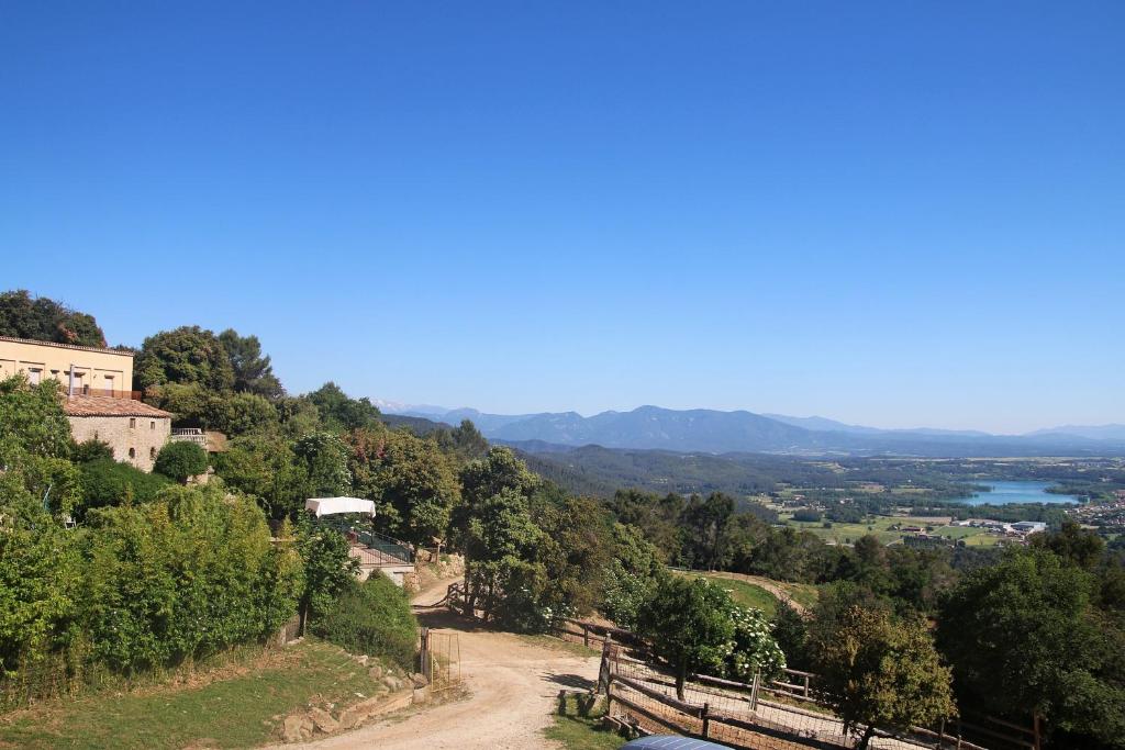 un camino de tierra en una colina con árboles y montañas en Can Serrallonga, en Camós