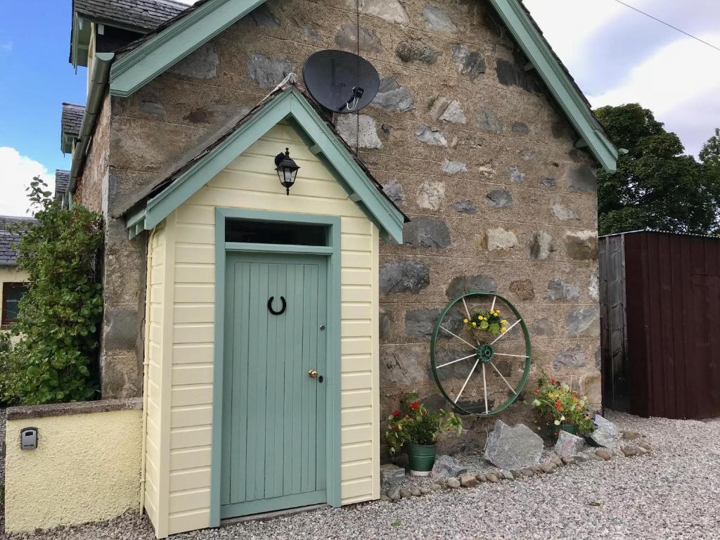 een schuur met een blauwe deur aan de zijkant van een gebouw bij Rosemount Bothy - Highland Cottage in Garve