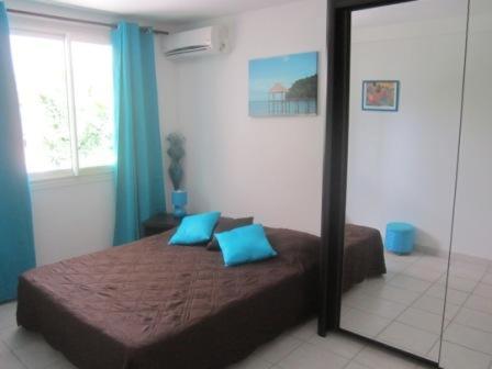 a bedroom with a bed with blue pillows and a mirror at Mary Madinina in Fort-de-France